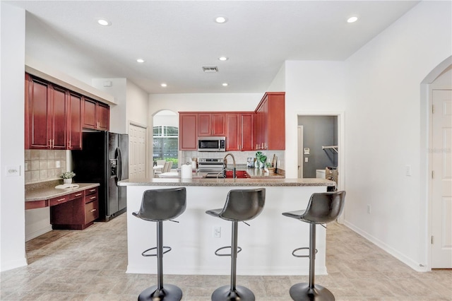 kitchen featuring sink, decorative backsplash, a kitchen bar, and stainless steel appliances