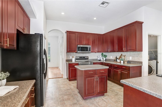 kitchen with decorative backsplash, appliances with stainless steel finishes, a center island, and washer / clothes dryer