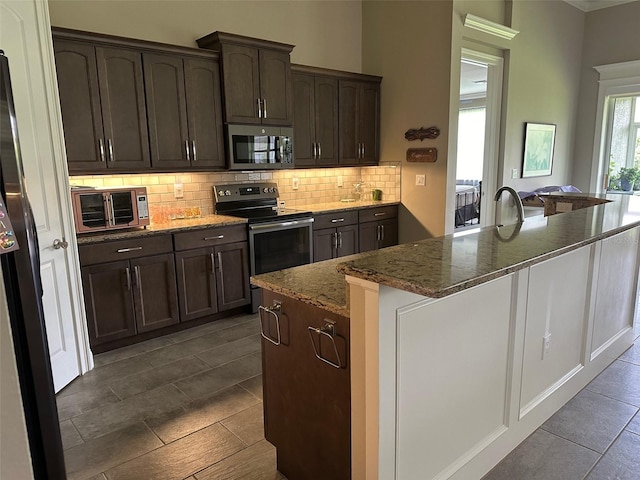 kitchen featuring stone countertops, dark brown cabinetry, stainless steel appliances, and an island with sink