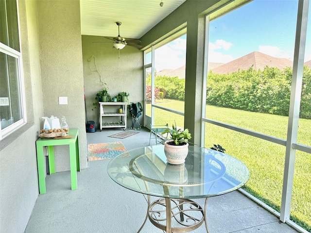 sunroom / solarium with a mountain view and ceiling fan