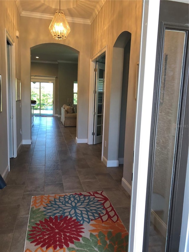 corridor featuring an inviting chandelier, arched walkways, and crown molding