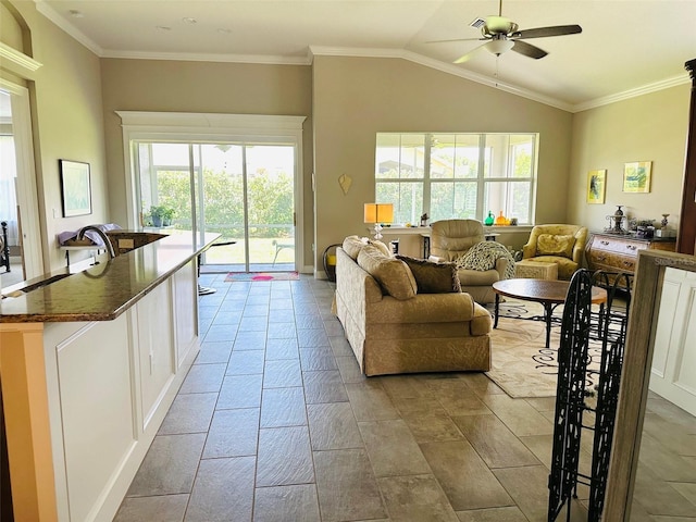 living room featuring baseboards, ceiling fan, vaulted ceiling, and a wealth of natural light