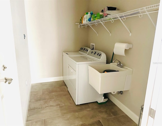 clothes washing area featuring laundry area, a sink, baseboards, light tile patterned floors, and separate washer and dryer