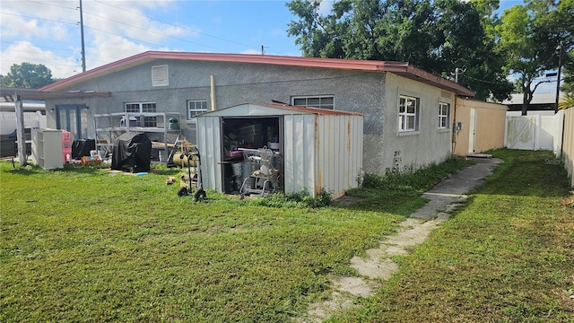 back of property with a lawn and a storage unit