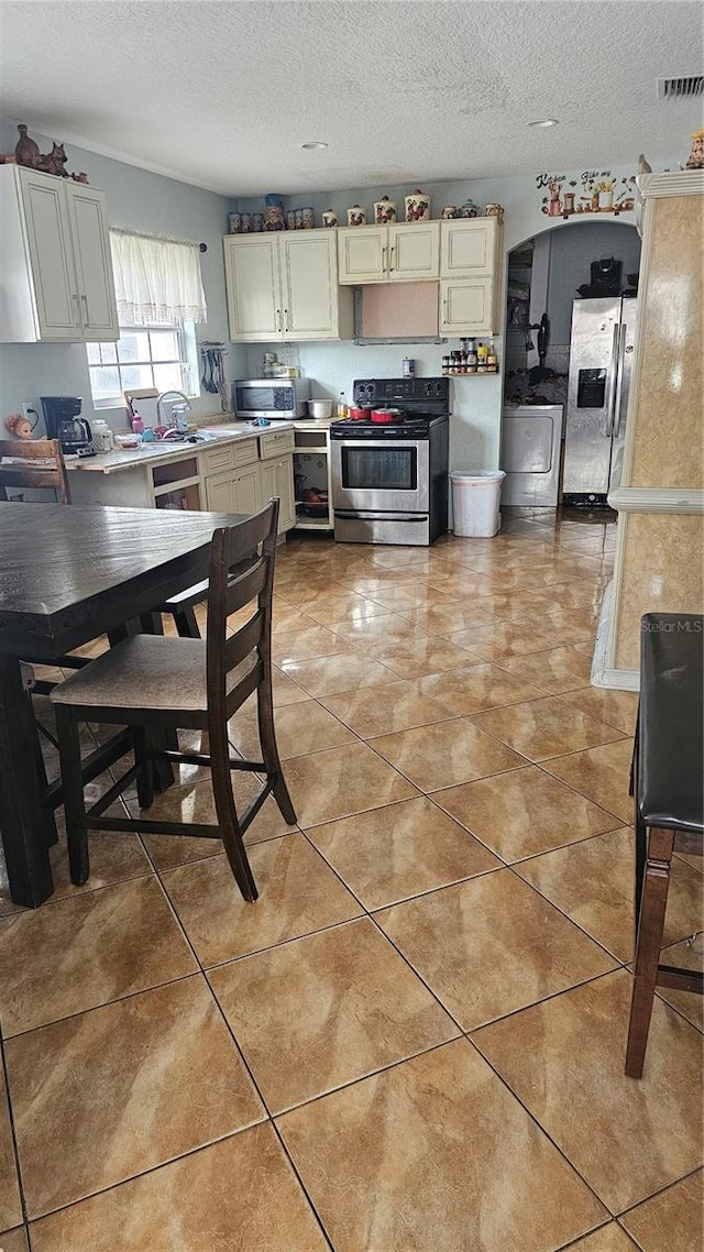 kitchen featuring a textured ceiling, light tile patterned floors, and appliances with stainless steel finishes