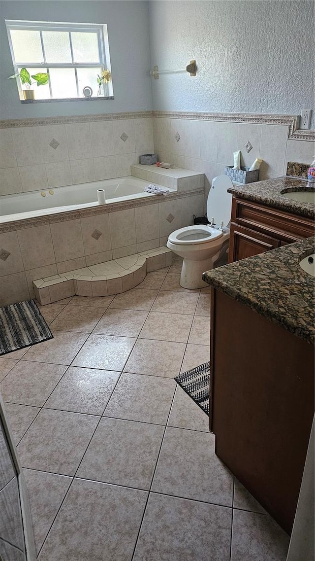 bathroom featuring toilet, vanity, tile patterned flooring, and tiled tub