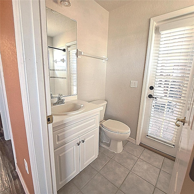 bathroom featuring tile patterned flooring, vanity, a tile shower, and toilet