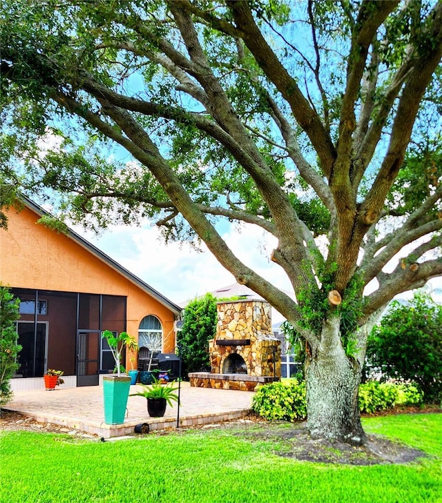 view of yard featuring a patio, a sunroom, and a fireplace