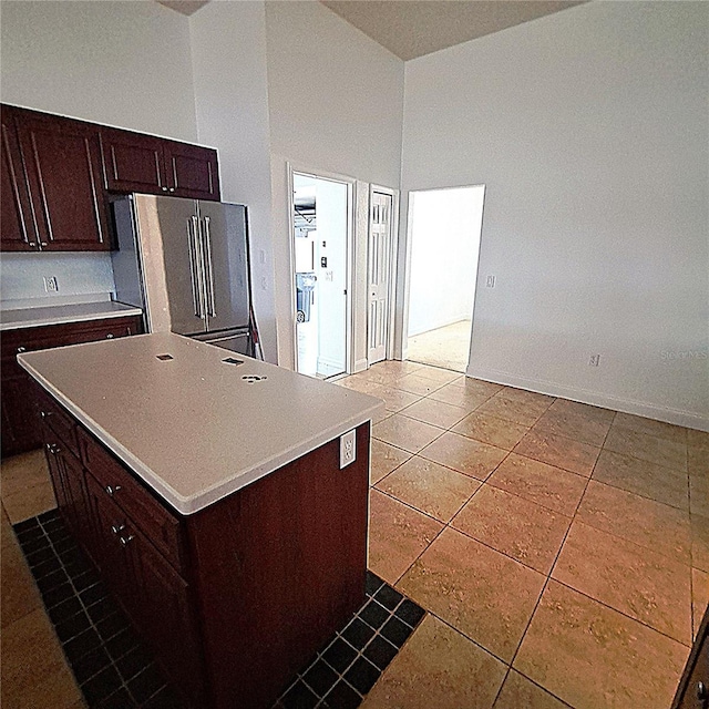 kitchen featuring high end fridge, tile patterned flooring, high vaulted ceiling, dark brown cabinetry, and a kitchen island