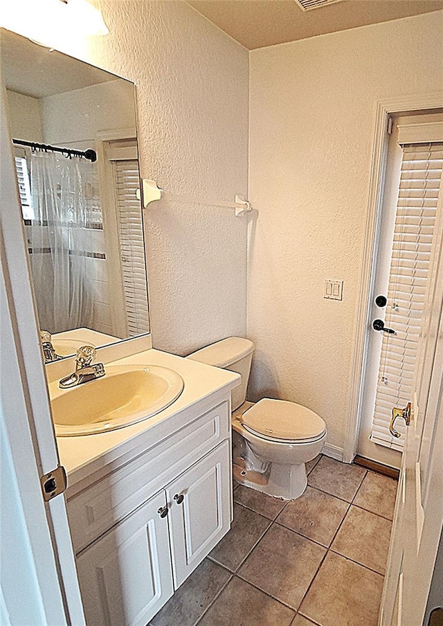 bathroom with vanity, walk in shower, tile patterned floors, and toilet