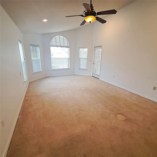 empty room featuring ceiling fan, vaulted ceiling, and light carpet