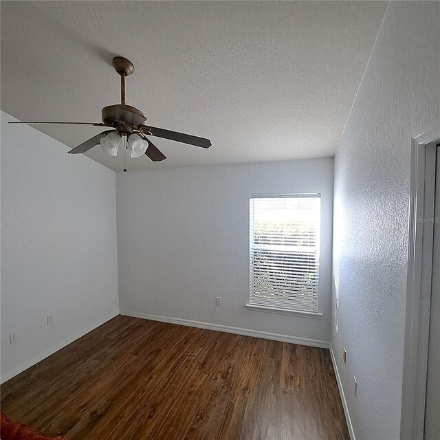 spare room featuring ceiling fan, dark wood-type flooring, and a textured ceiling