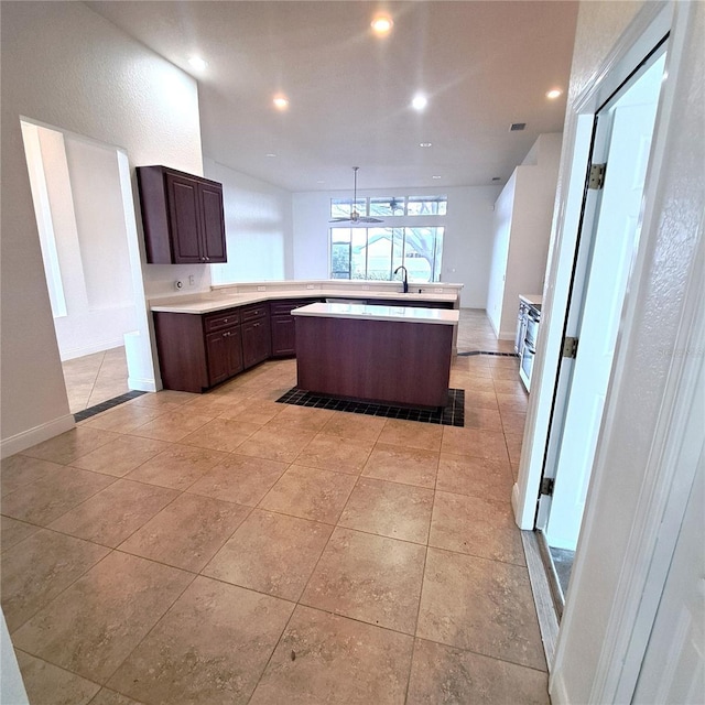 kitchen with pendant lighting, sink, a center island, light tile patterned floors, and dark brown cabinets