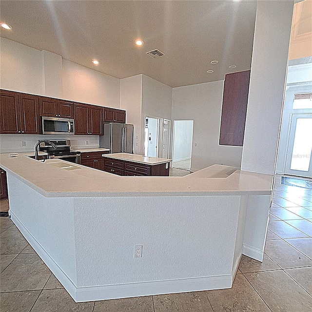 kitchen featuring sink, light tile patterned floors, a center island, and appliances with stainless steel finishes