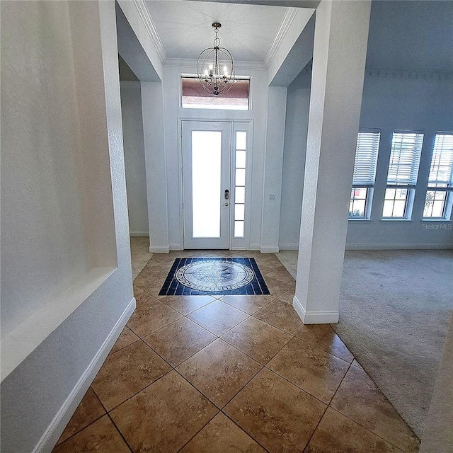 carpeted entrance foyer featuring crown molding and a chandelier