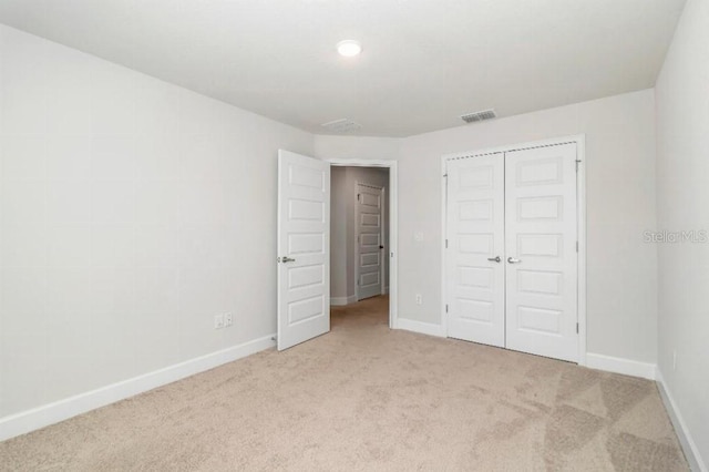 unfurnished bedroom with light carpet and a closet