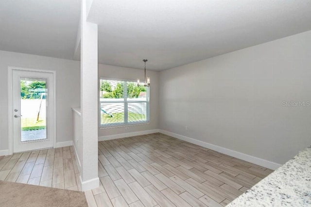 spare room featuring light wood-type flooring and a chandelier