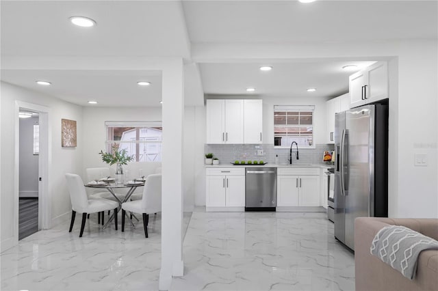 kitchen with tasteful backsplash, sink, white cabinets, and appliances with stainless steel finishes