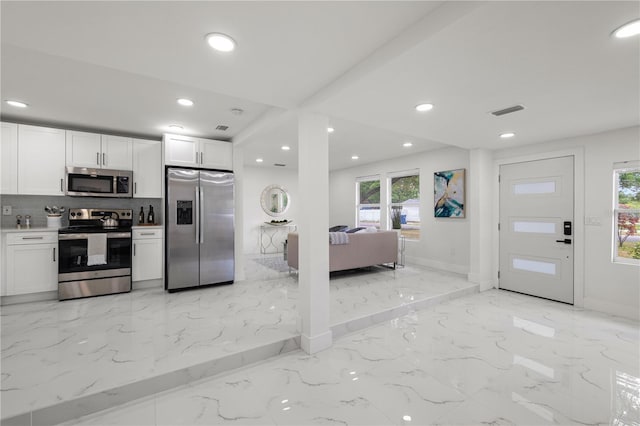 kitchen featuring decorative backsplash, white cabinetry, and stainless steel appliances