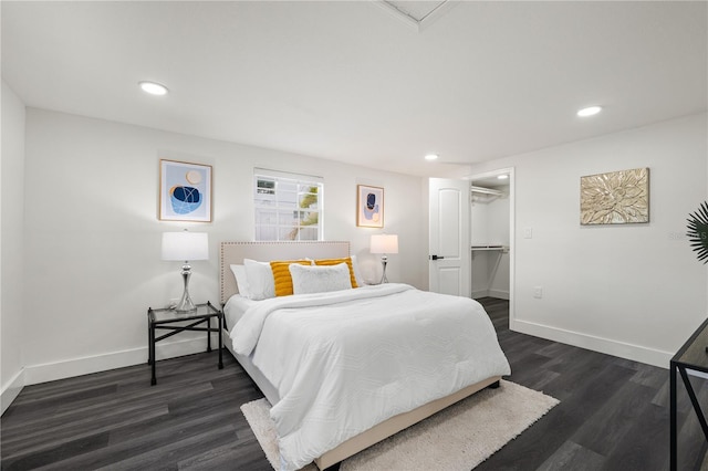 bedroom featuring a walk in closet, dark wood-type flooring, and a closet