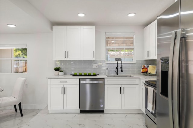 kitchen with decorative backsplash, sink, white cabinetry, and stainless steel appliances