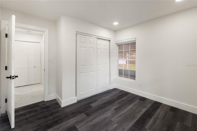 unfurnished bedroom with dark hardwood / wood-style floors and a closet