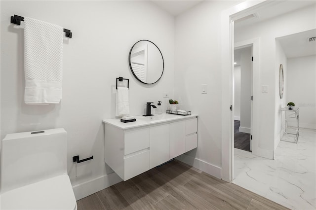 bathroom with hardwood / wood-style flooring, vanity, and toilet