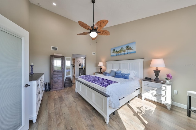 bedroom with ceiling fan, high vaulted ceiling, and light hardwood / wood-style flooring