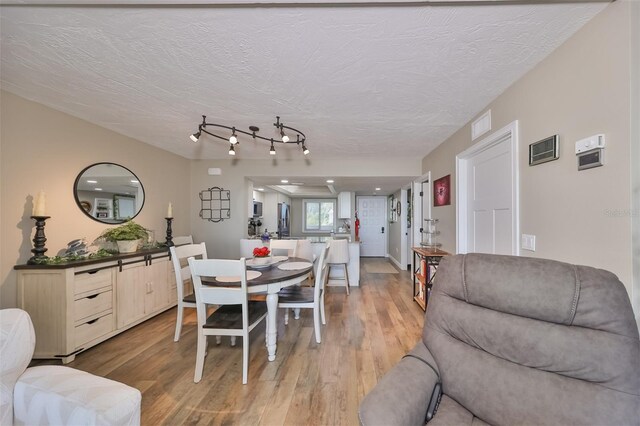 dining space with wood-type flooring and a textured ceiling