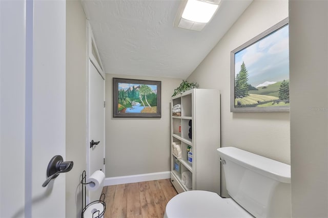 bathroom with lofted ceiling, hardwood / wood-style flooring, and toilet