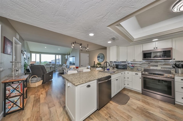 kitchen featuring stainless steel appliances, white cabinetry, sink, and kitchen peninsula