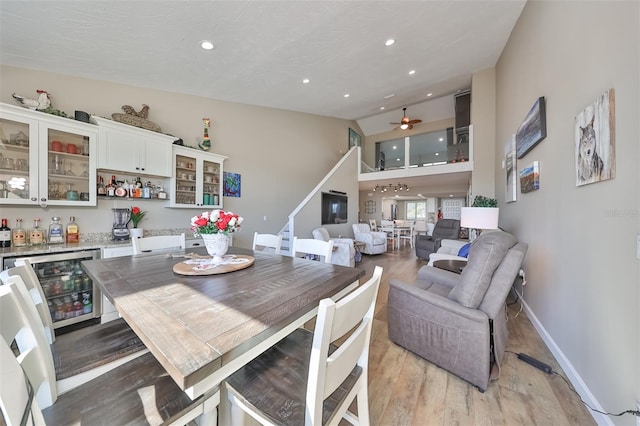 dining room featuring wine cooler, light hardwood / wood-style floors, ceiling fan, and indoor bar