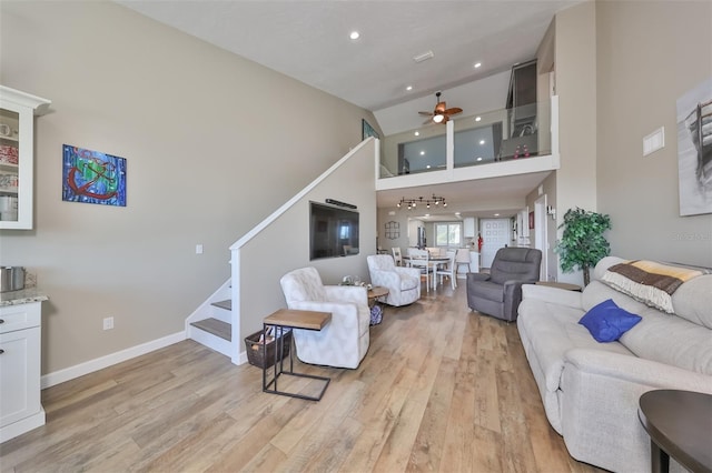 living room featuring ceiling fan, a towering ceiling, and light hardwood / wood-style floors