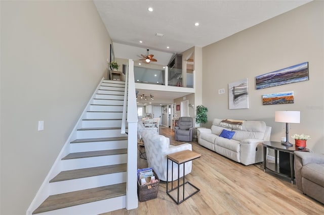 living room with light hardwood / wood-style floors, ceiling fan, and a high ceiling