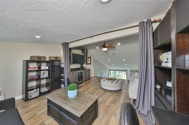 living room with wine cooler, ceiling fan, lofted ceiling, and light wood-type flooring