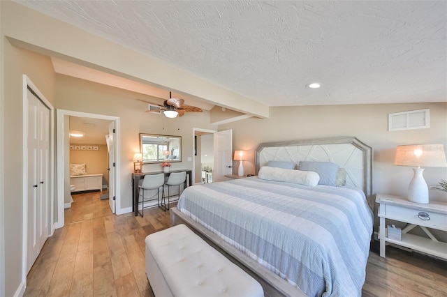 bedroom with vaulted ceiling, hardwood / wood-style flooring, ceiling fan, a textured ceiling, and a closet