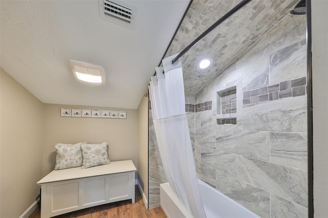 bathroom featuring hardwood / wood-style flooring, lofted ceiling, and shower / bath combination with curtain