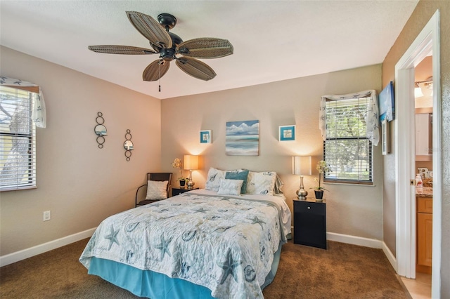 carpeted bedroom featuring ceiling fan, multiple windows, and ensuite bath