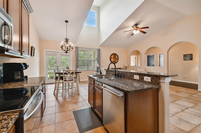 kitchen featuring appliances with stainless steel finishes, ceiling fan with notable chandelier, sink, pendant lighting, and a center island with sink