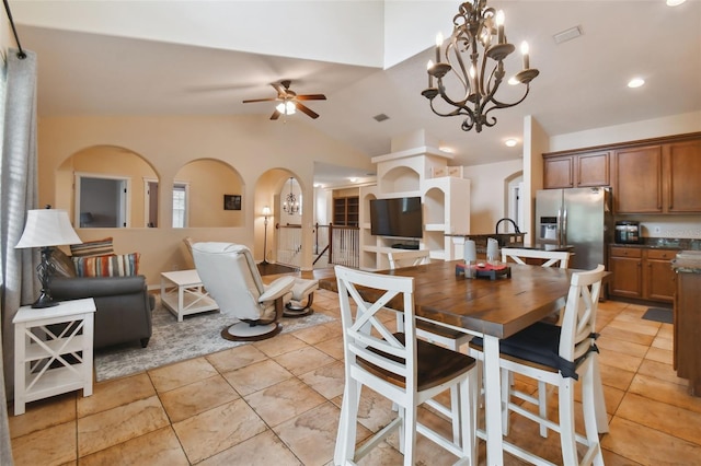 dining area featuring ceiling fan with notable chandelier and vaulted ceiling