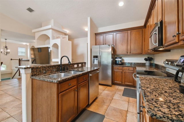 kitchen with sink, hanging light fixtures, lofted ceiling, light tile patterned floors, and appliances with stainless steel finishes