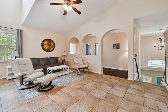 living room with ceiling fan with notable chandelier and high vaulted ceiling