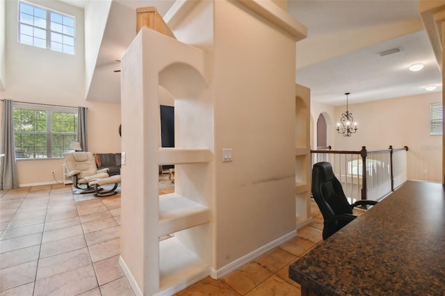 office with light tile patterned flooring, a high ceiling, and an inviting chandelier