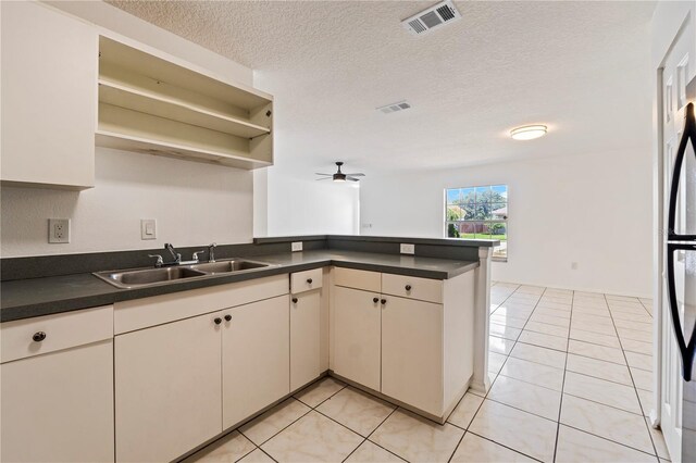 kitchen featuring light tile flooring, kitchen peninsula, ceiling fan, sink, and a textured ceiling