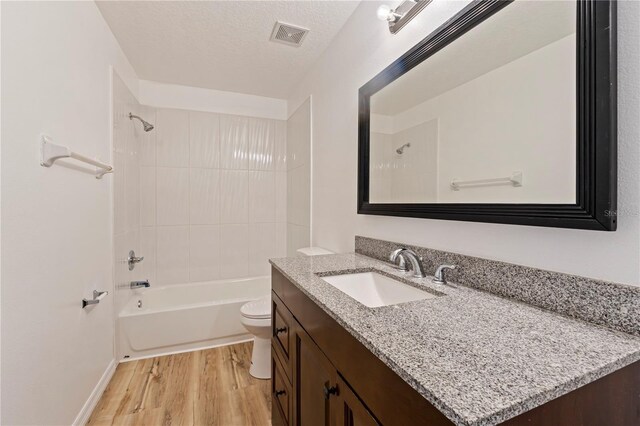 full bathroom with a textured ceiling, hardwood / wood-style floors, tub / shower combination, vanity, and toilet