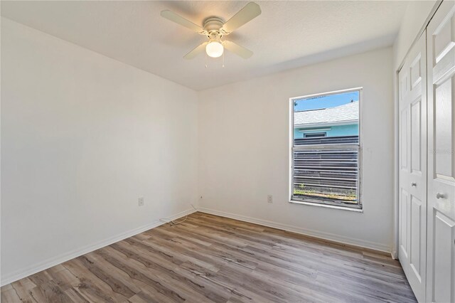 unfurnished bedroom featuring wood-type flooring, a closet, ceiling fan, and multiple windows