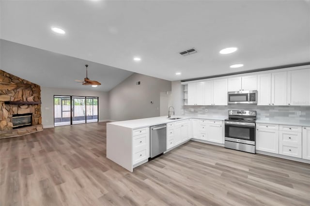 kitchen with sink, white cabinets, decorative backsplash, kitchen peninsula, and stainless steel appliances