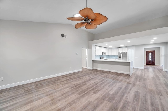 unfurnished living room featuring ceiling fan, lofted ceiling, and light wood-type flooring