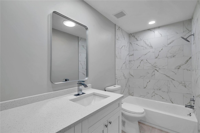 full bathroom featuring tiled shower / bath, vanity, and toilet