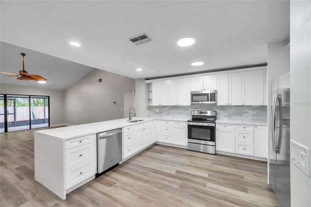 kitchen with lofted ceiling, sink, backsplash, kitchen peninsula, and stainless steel appliances